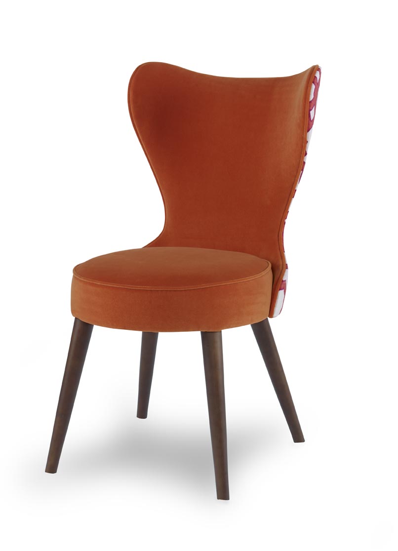 The Maribella Chair in Marmalade Velvet with Custom COM back sits in a studio.